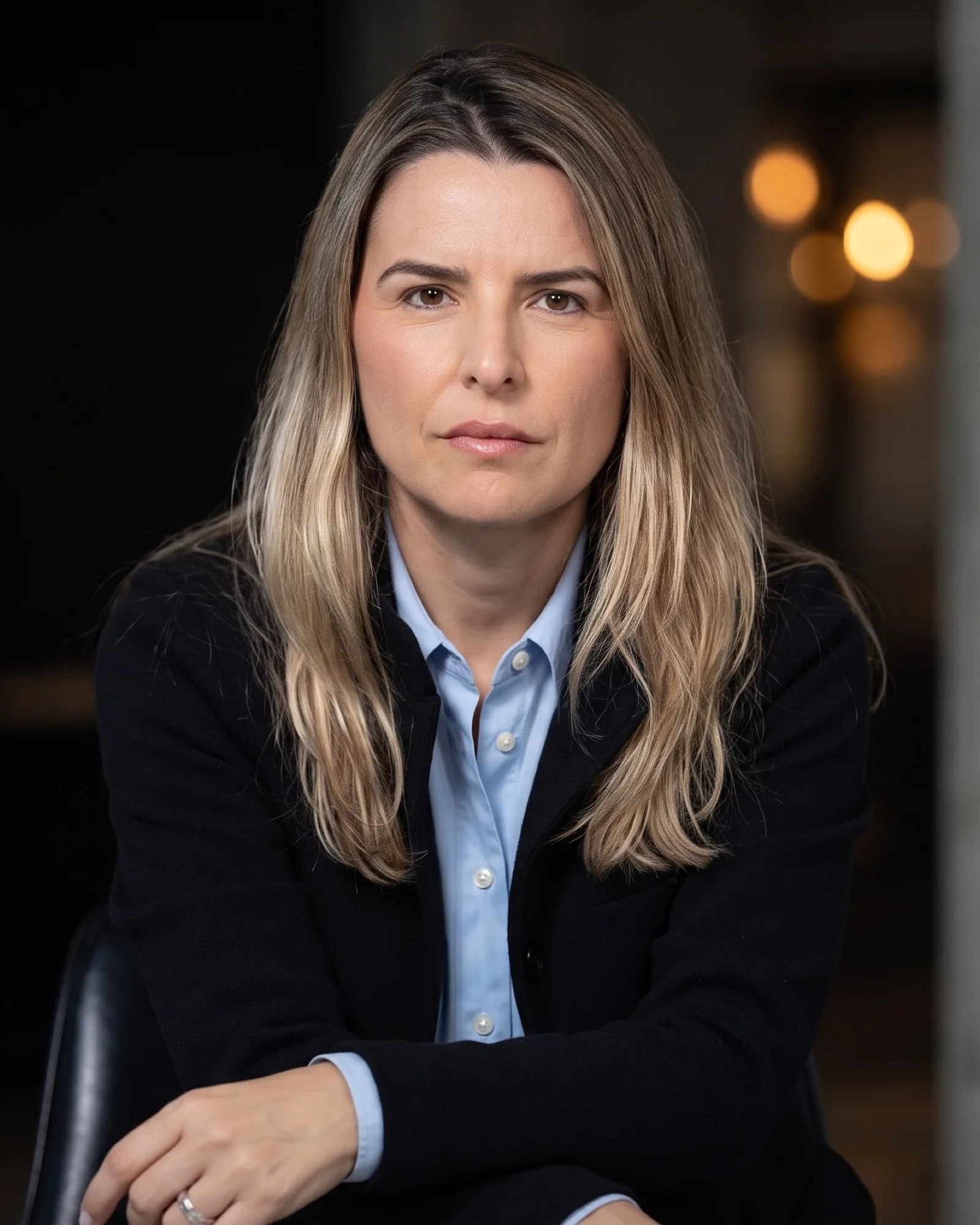 Andreza Araújo，身穿黑色西装外套和蓝色衬衫